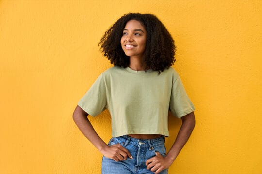 Teen smiling confidently with hands on hips.